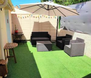 a patio with two couches and an umbrella at Maison T2 proche mer jardin et parking securise in Six-Fours-les-Plages