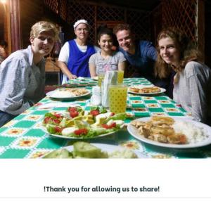 eine Gruppe von Menschen, die an einem Tisch mit Essen sitzen in der Unterkunft Eco Guest House- Sarapiquí 2 in Sarapiquí