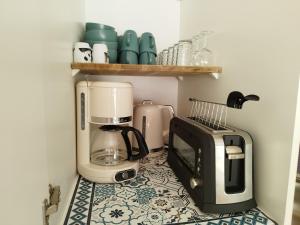 a kitchen with a coffee maker and a microwave on a tile floor at Studio Coco Zen in Sainte-Anne