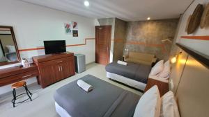 a small room with two beds and a television at Sandat Hotel Legian in Legian