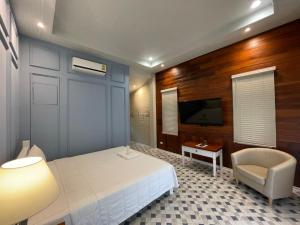 1 dormitorio con 1 cama, 1 silla y TV en Aob-Oun Homestay, en Pak Chong