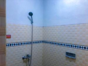 a bathroom with a shower with a fan on the wall at Twentynine Homestay in Banyuwangi