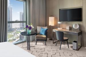 a hotel room with a desk and a television at Address Grand Creek Harbour in Dubai