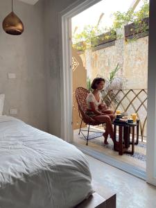 a woman sitting on a bed in front of a window at Layla Tulum - Adults Only in Tulum