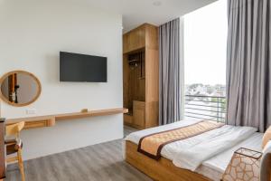 um quarto de hotel com uma cama e uma televisão em Khang Hy Hotel em Buôn Enao