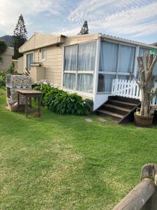 ein Haus mit einer Veranda und einem Tisch im Hof in der Unterkunft Beach Cottage in Kleinmond