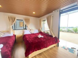 um quarto com 2 camas com lençóis vermelhos e uma janela em Ngọc Nguyên Homestay em Da Lat