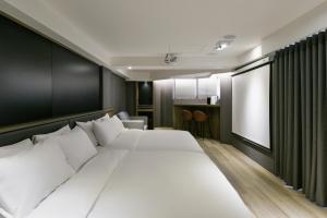 una camera da letto con un grande letto bianco e una finestra di Autumn Willow Hotel a Taichung