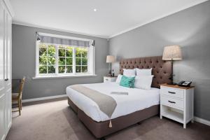 um quarto com uma cama grande e uma janela em Parklands Country Gardens & Lodges Blue Mountains em Blackheath