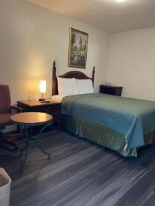 a hotel room with a bed and a table and a chair at Economy Inn Paso Robles in Paso Robles