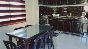 Avana Hills Boracay Prime Grand Suite في بوراكاي: مطبخ مع طاولة وكراسي زجاجية
