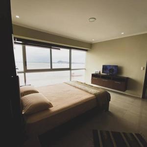 1 dormitorio con 1 cama grande y TV en 5-luxury suite Riverfront Vista al río, en Guayaquil