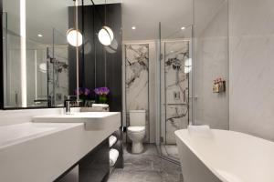 a bathroom with two sinks and a toilet and a shower at Crowne Plaza Shanghai Nanjing Road by IHG in Shanghai
