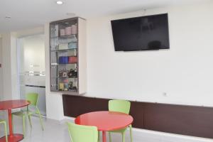 a waiting room with tables and chairs and a flat screen tv at Homestay 82 Syariah Palembang in Palembang