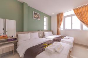 une chambre d'hôtel avec deux lits et un miroir dans l'établissement Dalat Joy Hotel, à Đà Lạt