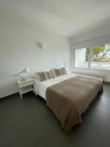 a white bedroom with a large bed and a window at Viva Sitges - Sitges View in Sitges
