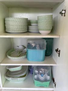two shelves with dishes and plates in a kitchen cabinet at West Sahara Beach House in Cabangan