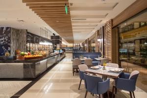 上海市にあるCrowne Plaza Shanghai Nanjing Road by IHGのテーブルと椅子のあるレストラン、ビュッフェ