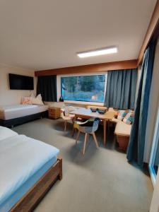 een slaapkamer met een bureau, een bed en een tafel bij Alpinum Hostel in Biberwier
