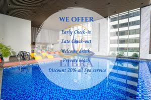 a pool with a sign that reads we offer early check in late check out welcome at Libra Nha Trang in Nha Trang