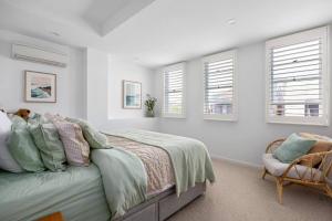 um quarto com uma cama, uma cadeira e janelas em Sandy@Village - newly renovated + bay views em Sandringham