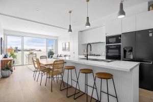 uma cozinha com uma mesa e algumas cadeiras e um balcão em Sandy@Village - newly renovated + bay views em Sandringham