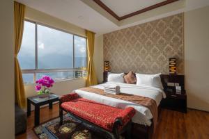 um quarto com uma cama grande e uma janela em HOTEL SHINKHAM GRAND em Gangtok