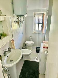 La salle de bains blanche est pourvue d'un lavabo et de toilettes. dans l'établissement apartmentinscalea, à Scalea