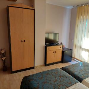 a bedroom with a bed and a cabinet and a television at Guest House Planinski Zdravets in Bansko