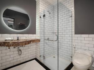 a bathroom with a toilet and a glass shower at Luminor Hotel Palembang by WH in Palembang