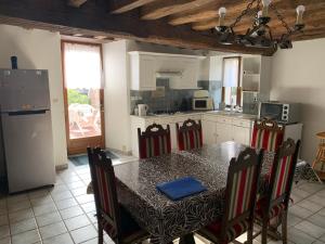 a kitchen with a table with chairs and a refrigerator at Maison indépendante à la campagne in Courcelles-sur-Vesle