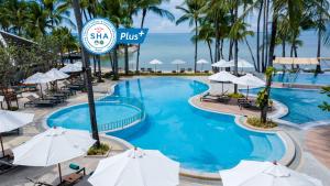 a pool at a resort with umbrellas and the ocean at Outrigger Koh Samui Beach Resort - SHA Extra Plus in Lamai