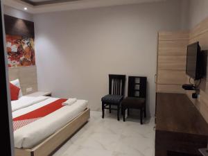 a bedroom with a bed and a chair and a television at Hotel MEGHA INN in Lucknow