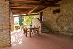 eine Terrasse mit einem Tisch, Stühlen und einer Ziegelwand in der Unterkunft Villa Il Fienile Il Sole Verde in Bucine