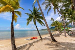 a beach with palm trees and a surfboard on it at Outrigger Koh Samui Beach Resort - SHA Extra Plus in Lamai