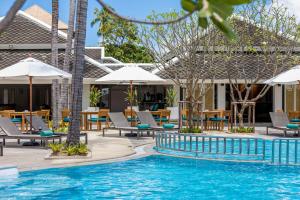 a pool at a hotel with chairs and tables and umbrellas at Outrigger Koh Samui Beach Resort - SHA Extra Plus in Lamai
