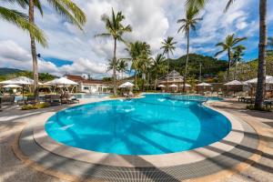 a large pool with palm trees and umbrellas at Outrigger Koh Samui Beach Resort - SHA Extra Plus in Lamai