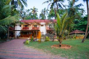a house with a palm tree in front of it at Club 7 Beach Resort in Kannur
