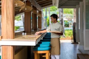 a man standing in front of a table at Outrigger Koh Samui Beach Resort - SHA Extra Plus in Lamai