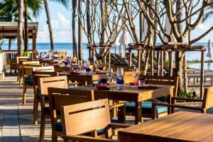 a restaurant with wooden tables and chairs and the ocean at Outrigger Koh Samui Beach Resort - SHA Extra Plus in Lamai