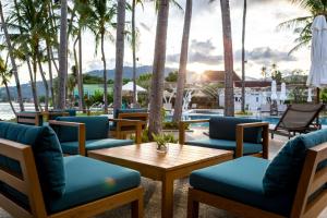 a patio with chairs and a table and palm trees at Outrigger Koh Samui Beach Resort - SHA Extra Plus in Lamai