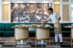a man standing at a table in a restaurant at Outrigger Koh Samui Beach Resort - SHA Extra Plus in Lamai