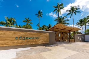 a sign in front of a building with palm trees at Outrigger Koh Samui Beach Resort - SHA Extra Plus in Lamai