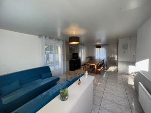 Maison Royan 3 chambres avec salle d'eau, piscine في رويان: غرفة معيشة مع أريكة زرقاء وطاولة