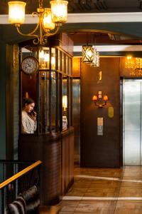 Un uomo che parla al cellulare in una stanza con un orologio di The Coach Hotel Sukhumvit - Asok BTS Bangkok by Compass Hospitality a Bangkok