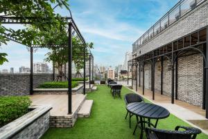 a patio with grass and tables and chairs on a building at Montraj Coach Sukhumvit Bangkok in Bangkok