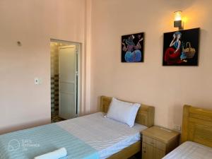 um quarto com duas camas e duas fotografias na parede em Cat Ba Sweet Potato Homestay em Ilha de Cát Bà