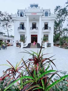 a large white building with two people in front of it at Villa Blueware - Venuestay in Vĩnh Phúc