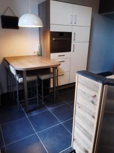 a kitchen with a wooden table and white cabinets at Maison cosy au centre de Nivelles in Nivelles