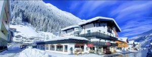 un edificio coperto di neve di fronte a una montagna di Bei die Gstrein's a See